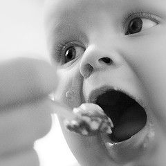 A picture of a baby opening it's mouth to eat.